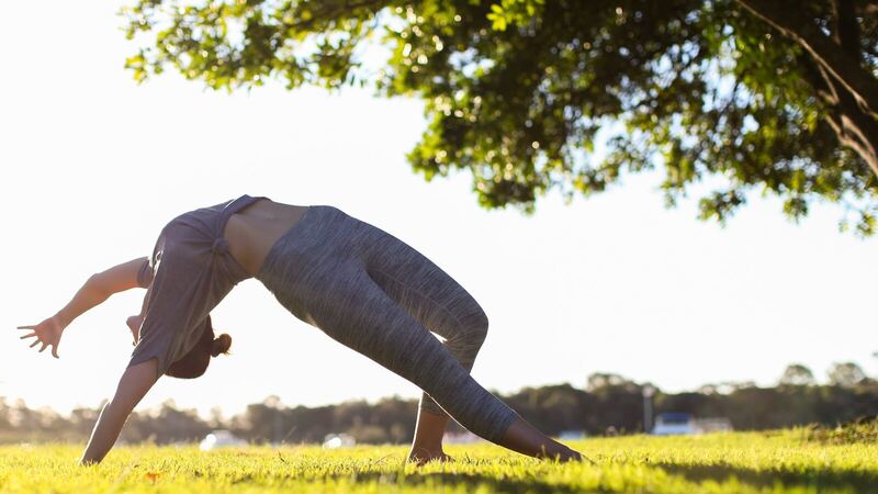 Jeune fille en bonne santé faisant du yoga dans un parc au soleil couchant.